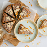 Taart met amandelschaafsel on top. Twee bordjes met taart erop en de rest van de taart ligt op een borrelplank.